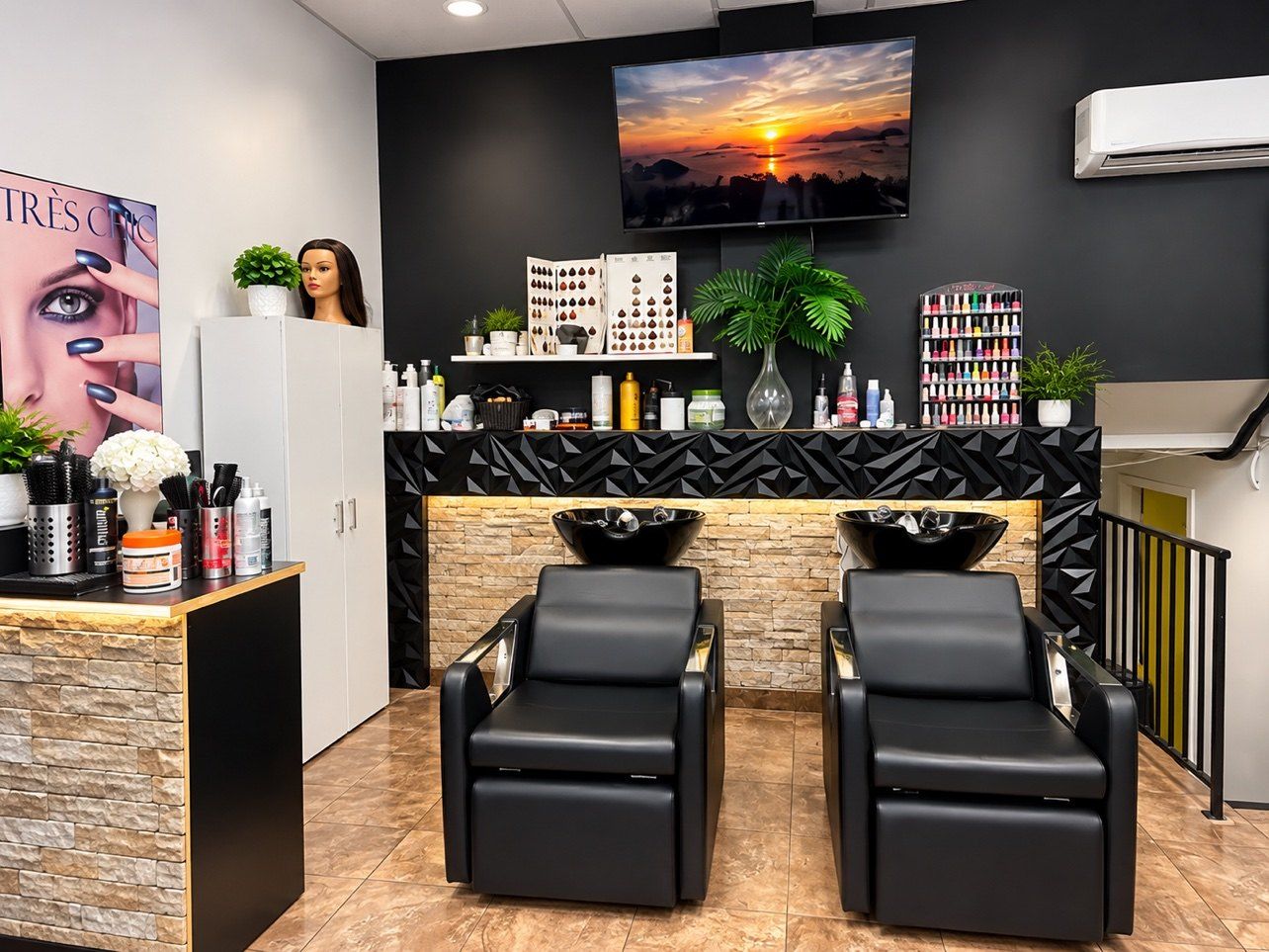 Espace de lavage du salon : deux fauteuils noirs avec bacs à shampoing, mur de pierre et présentoir de vernis